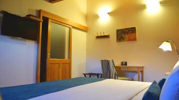 A hotel room with a bed, a desk, a chair, a TV, and a painting on the wall.