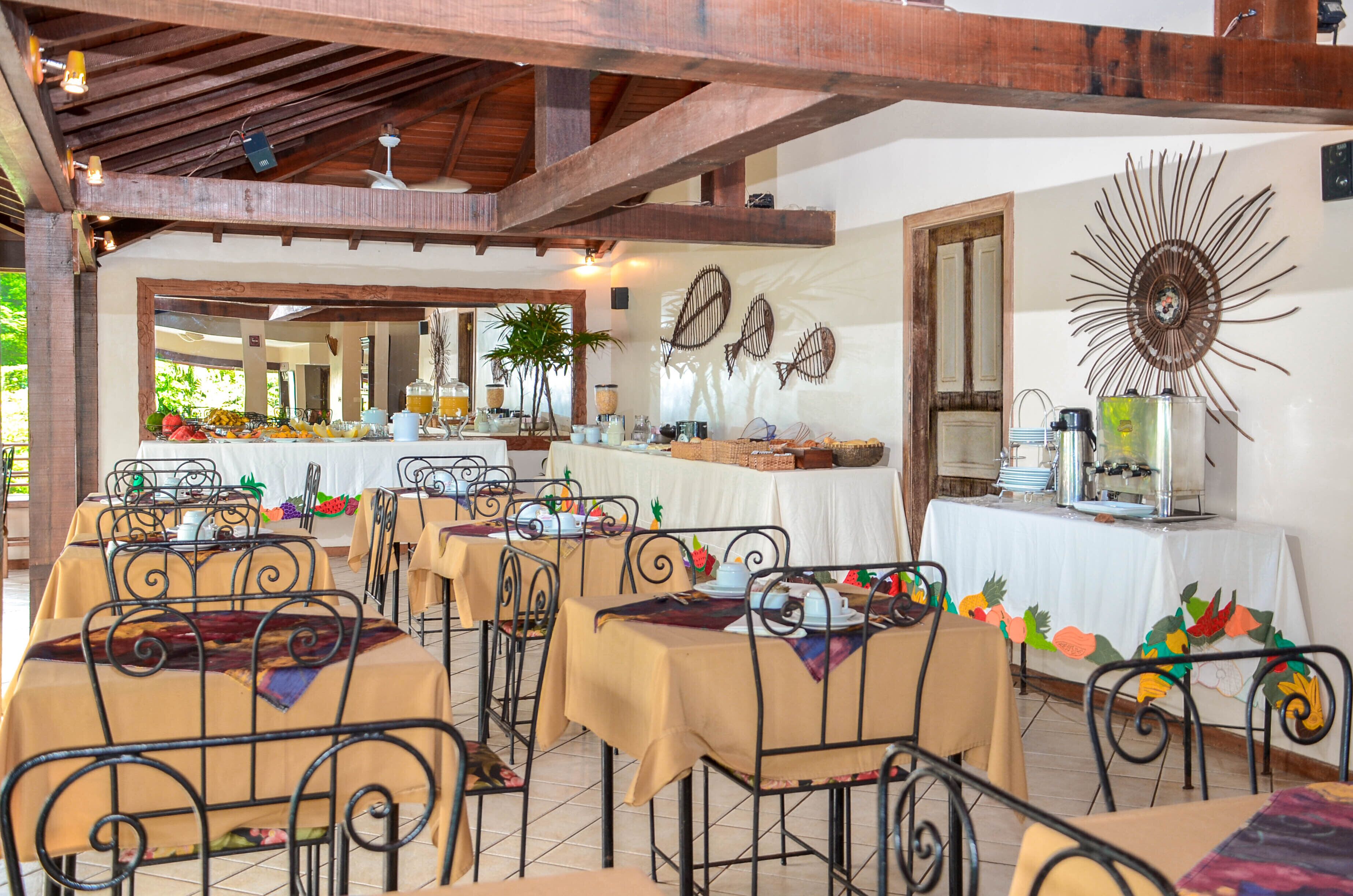 A restaurant with tables set for dining, a buffet area in the background, and decorative wall art.