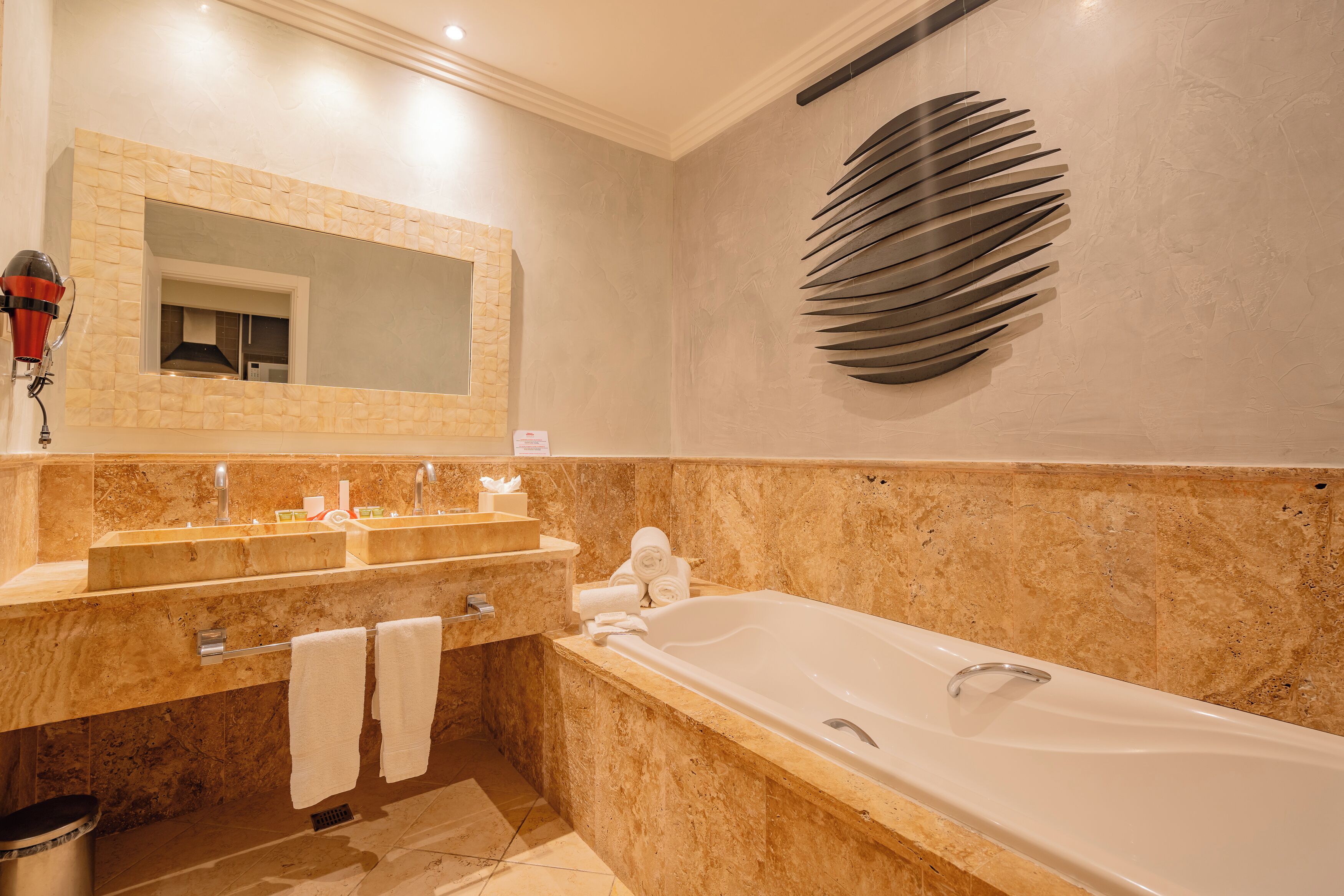 Ein Badezimmer mit einer großen Badewanne, einem Doppelwaschbecken und einem Spiegel.