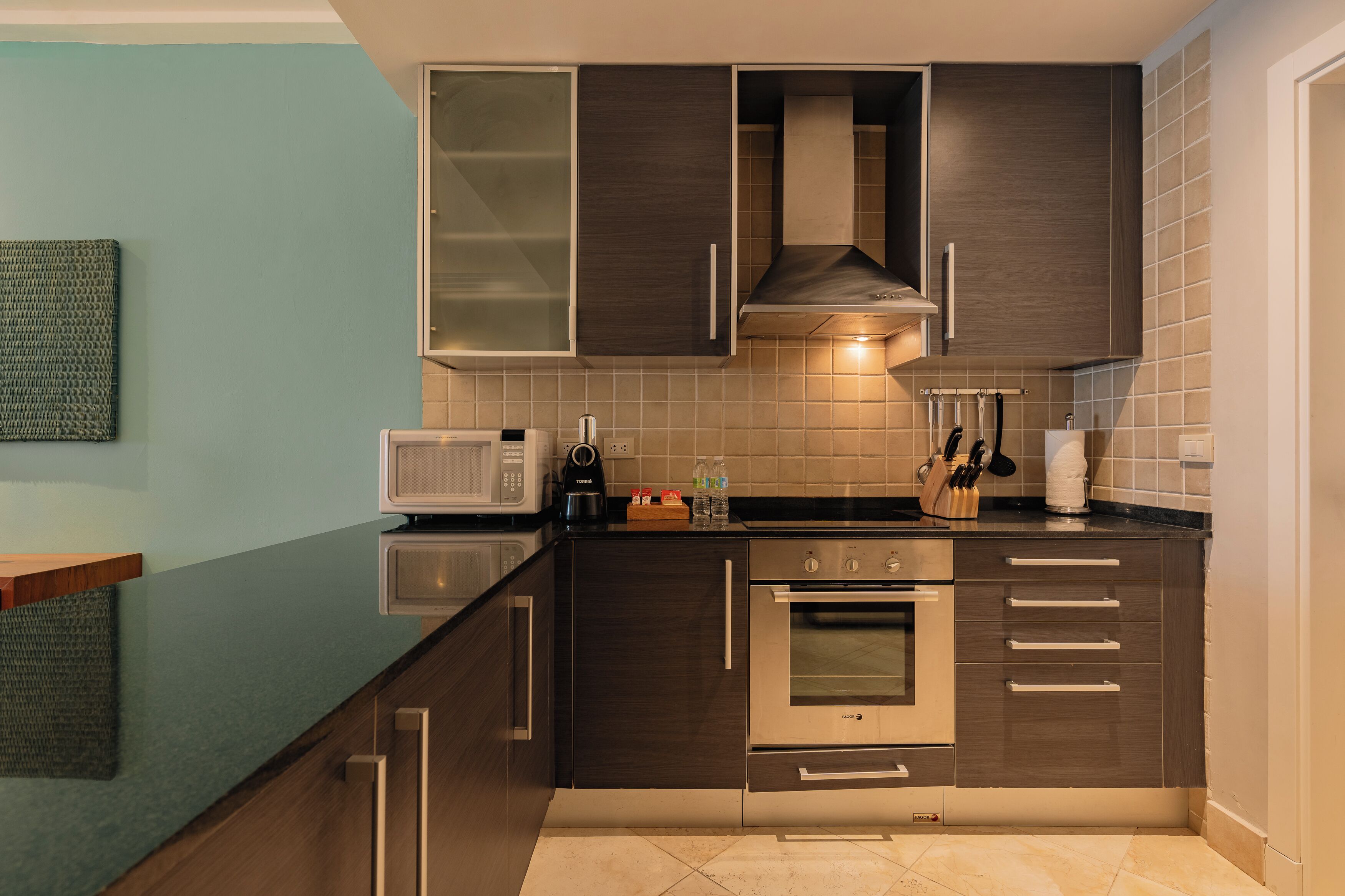Una cocina moderna con armarios oscuros, microondas, horno y cafetera.