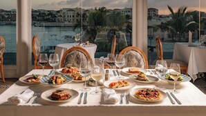 Une table dressée pour le dîner, avec vue sur un port et des bâtiments.