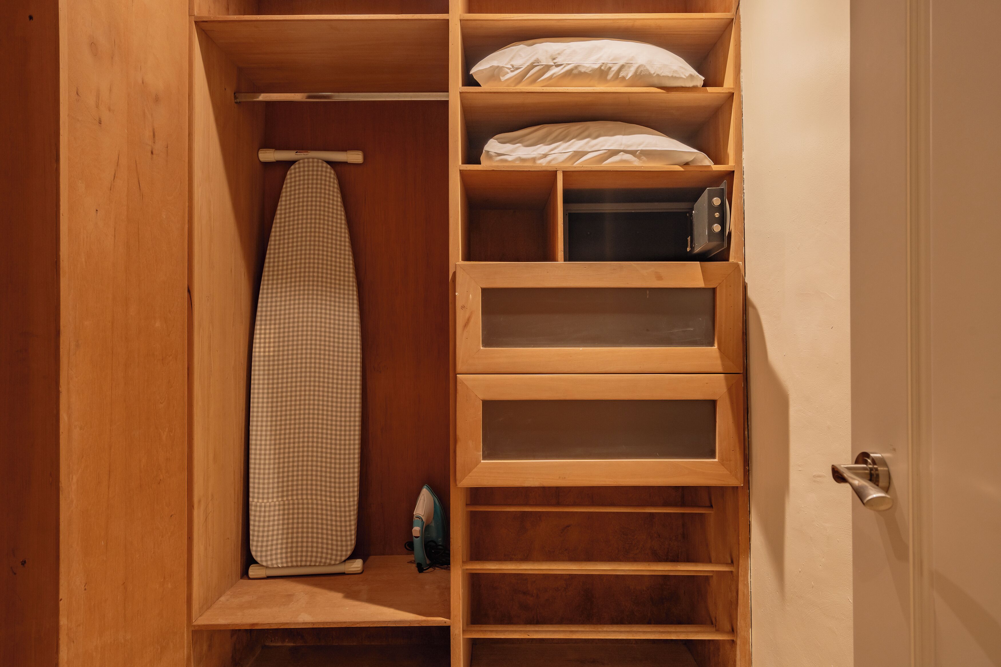 Un armario de madera con estantes, un planchador y un microondas.