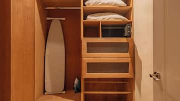 Un armario de madera con estantes, un planchador y un microondas.