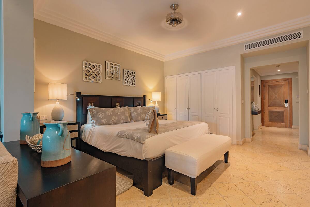 Une chambre à coucher comprenant un lit, des tables de chevet, des lampes, des vases décoratifs et une armoire.