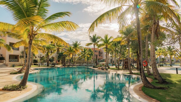 Une piscine entourée de palmiers et un bâtiment doté de balcons.