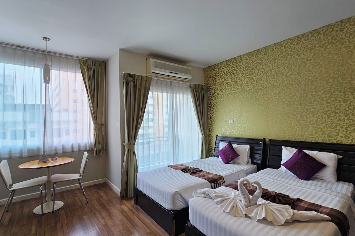 Une chambre d’hôtel avec deux lits, une petite table et une chaise.