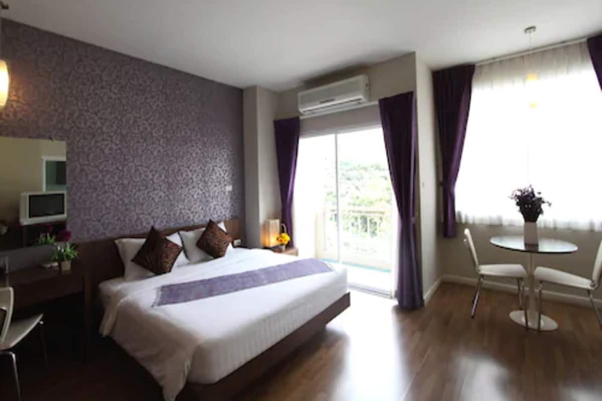 Une chambre d’hôtel avec un lit, un bureau, une chaise, une petite table et un balcon avec vue.