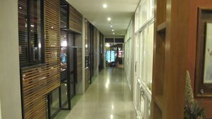 A hallway with wooden paneling and glass doors, leading to a room with a bed and a nightstand.