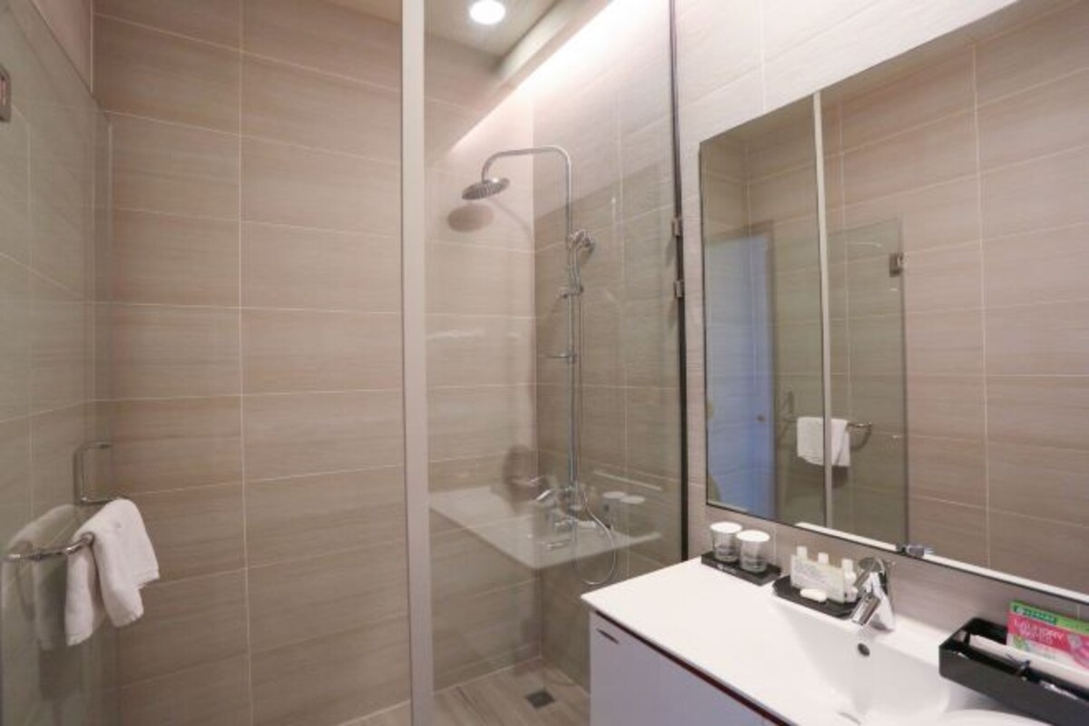 A modern bathroom with a glass-enclosed shower, a white sink, and a large mirror.