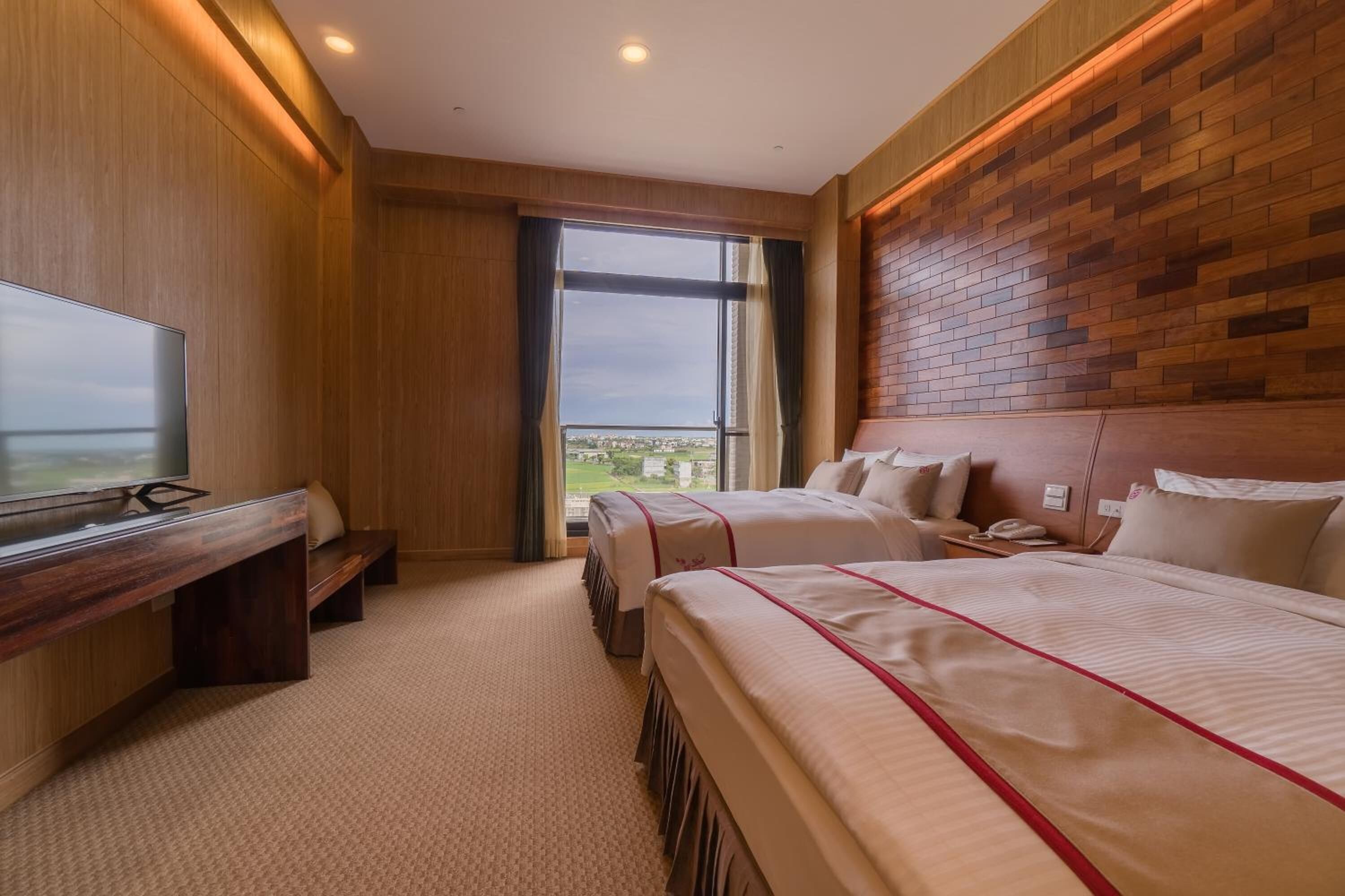 Habitación de hotel con una cama grande, un escritorio, un televisor y vista a la ciudad.