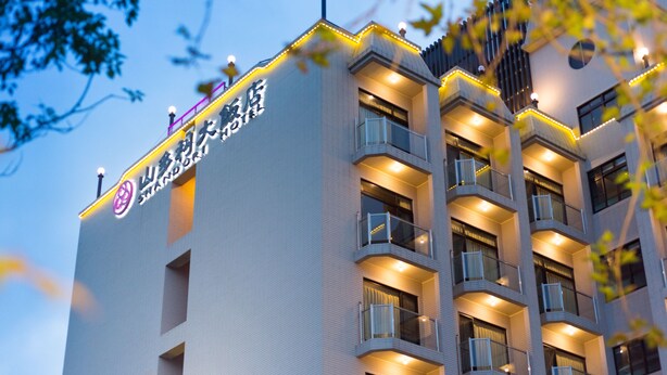 Un moderno edificio de hotel con varios balcones y señalización iluminada.