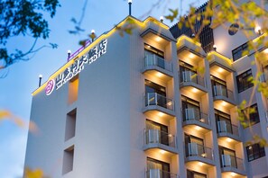 Un hôtel moderne doté de nombreux balcons et d’une enseigne lumineuse.