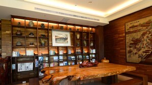 Un interior de madera con una mesa central, estanterías con libros y objetos decorativos, y un cuadro enmarcado en la pared.