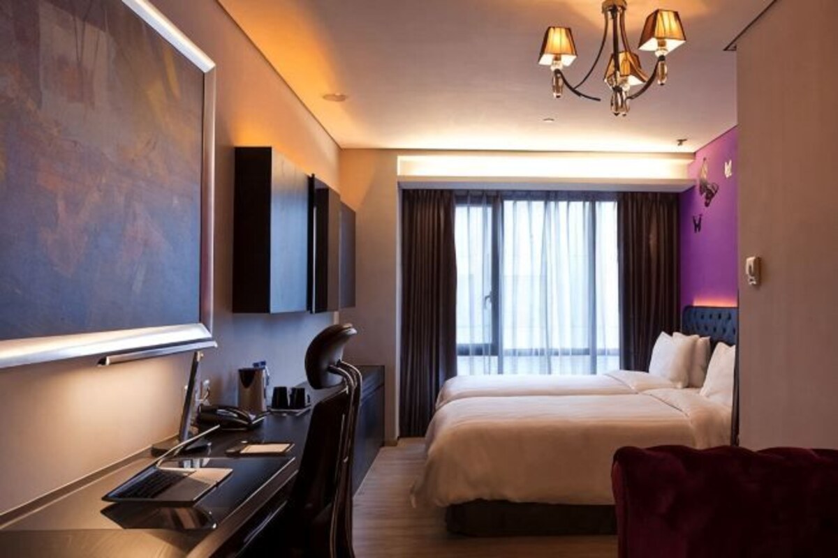 Una habitación de hotel con cama, escritorio y un cuadro grande en la pared.