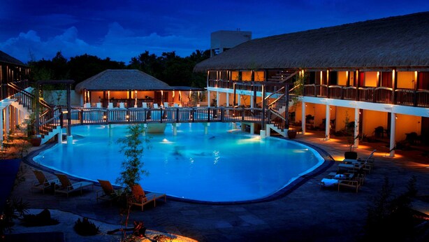 A swimming pool with lounge chairs and a building with a thatched roof. - Bluewater Panglao Beach Resort (Panglao)