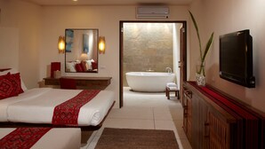 A modern hotel room with a large bed, a sitting area, a bathroom with a bathtub, and a flat-screen TV. - Bluewater Panglao Beach Resort (Panglao)