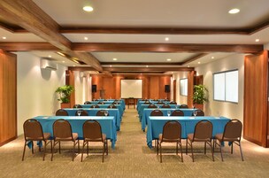 A conference room with multiple tables and chairs, wooden paneling, and ceiling lights.