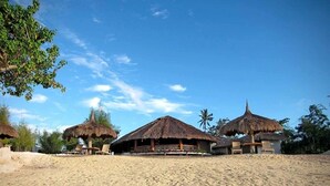 A beach resort with thatched-roof huts, sandy beach, and palm trees. - Bluewater Panglao Beach Resort (Panglao)