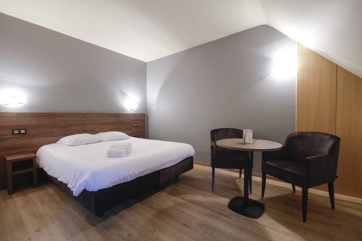 Une chambre à coucher comprenant un lit, une table de chevet, une chaise et une petite table ronde.