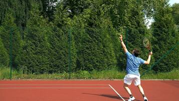 Una cancha de tenis con una red y un jugador en pleno movimiento.