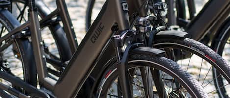 Una fila de bicicletas eléctricas estacionadas sobre un camino adoquinado.