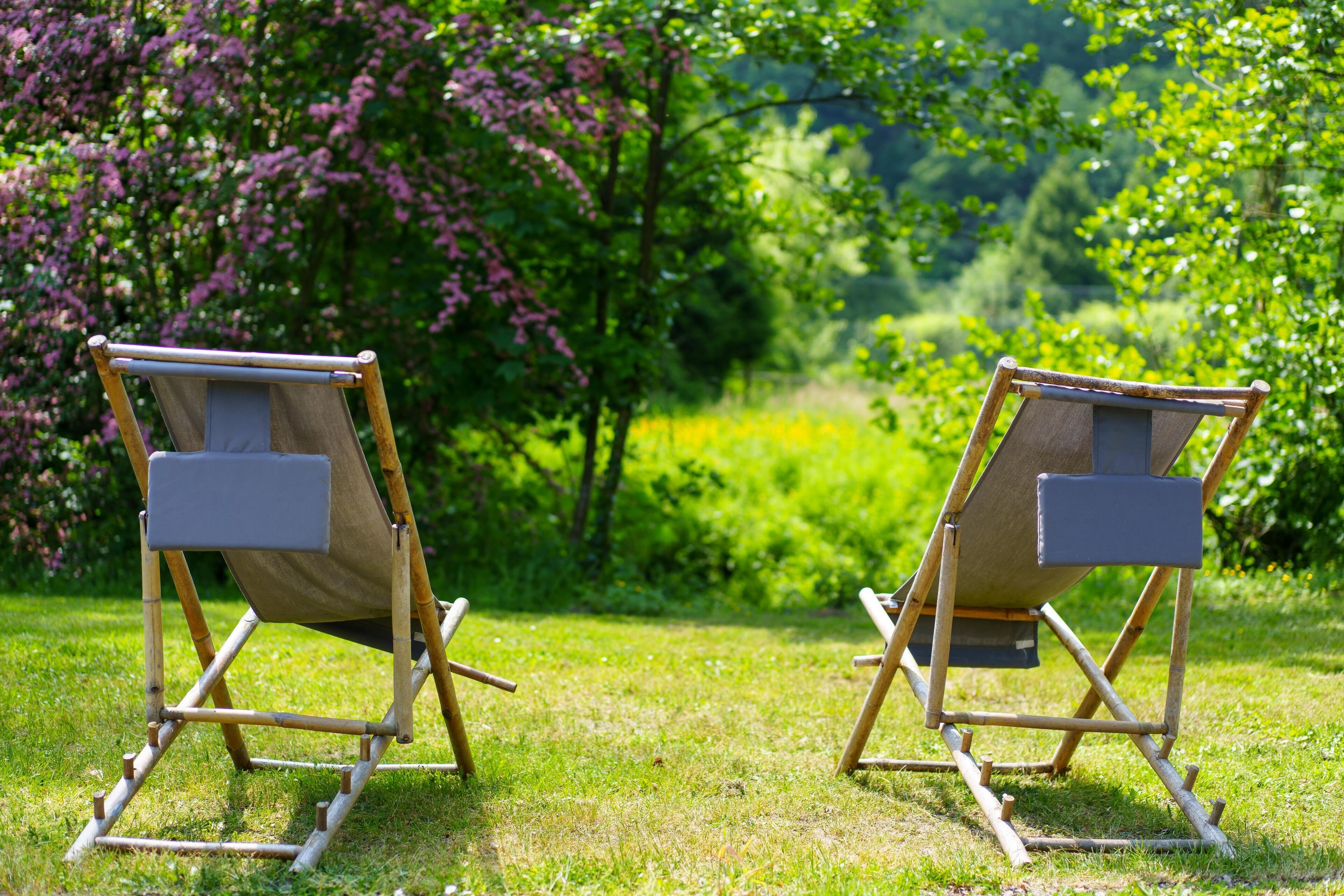 Deux chaises en toile, placées dans un cadre extérieur, avec une pelouse et des arbres en arrière-plan.