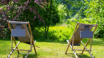 Deux chaises en toile, placées dans un cadre extérieur, avec une pelouse et des arbres en arrière-plan.