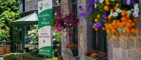 A hotel reception sign with a green and white color scheme, a website URL, and a phone number.