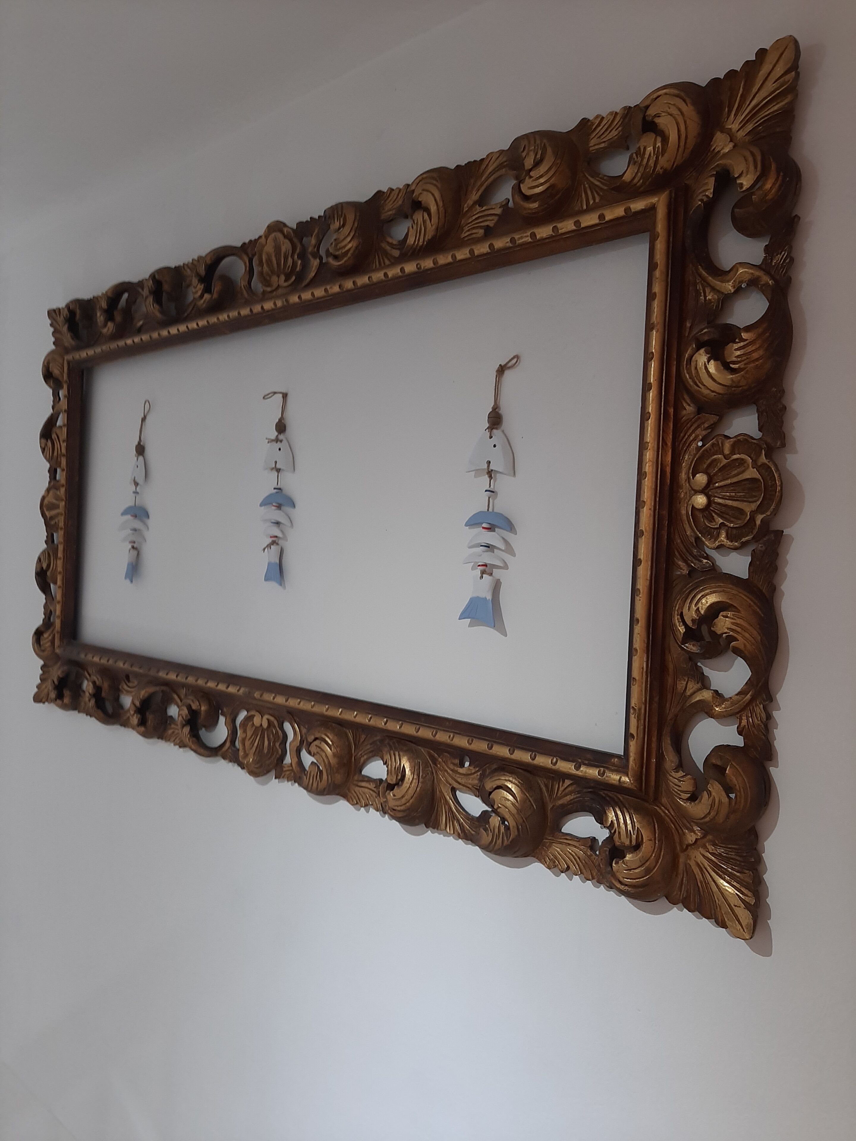 Une œuvre d’art encadrée, agrémentée de trois ornements suspendus.