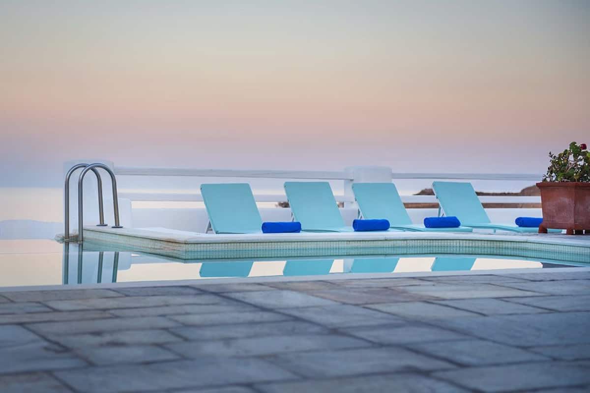 A poolside area with lounge chairs and a clear view of the sea.