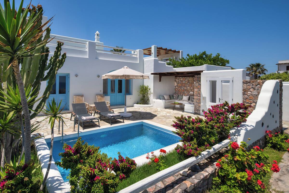 A poolside area with a white building, blue doors, and a stone wall.
