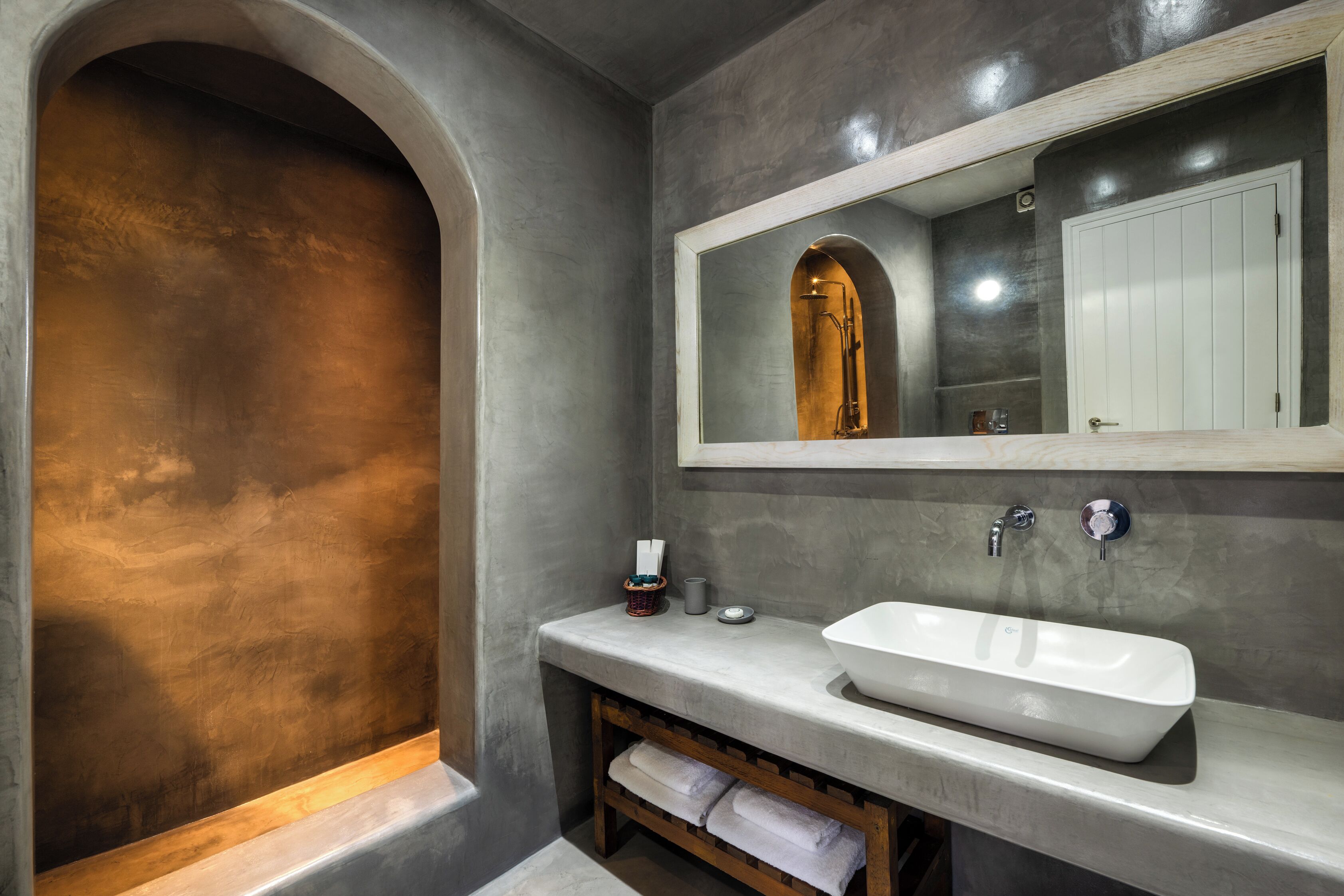 Un baño moderno con un amplio arco, un lavamanos blanco y un espejo sobre él.