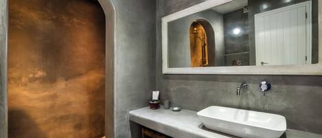 Un baño moderno con un amplio arco, un lavamanos blanco y un espejo sobre él.