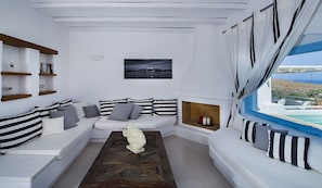 Relax in this stylish living room with a sofa, framed artwork, and a window offering a view of the sea.