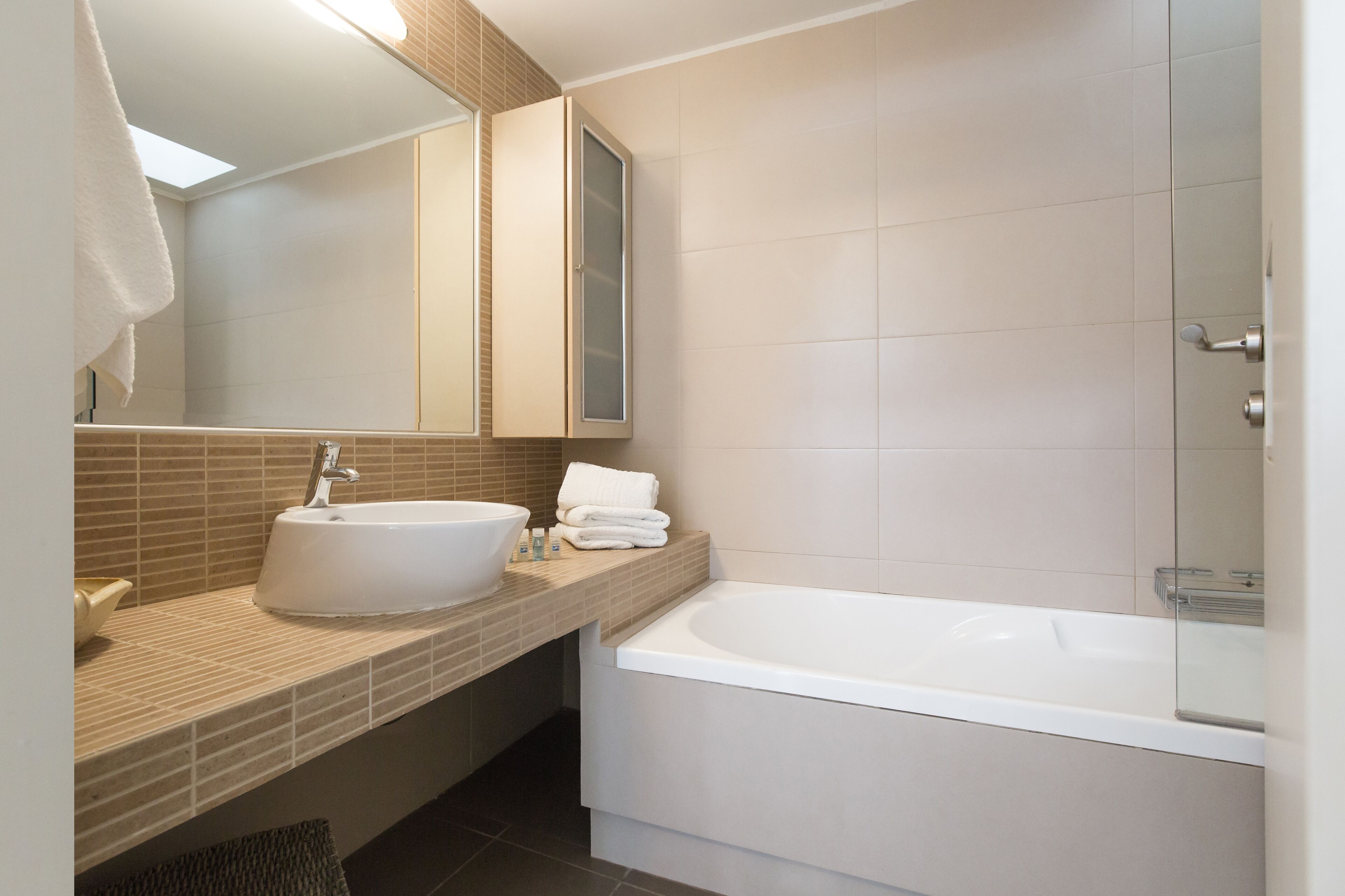 A modern bathroom with a large sink, a bathtub, and a mirror.