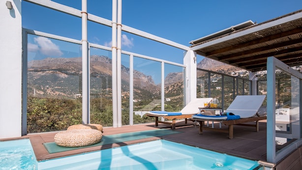Un espace piscine offrant une vue dégagée sur les montagnes, avec des chaises longues et une terrasse en bois.