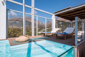 A pool area with clear views of mountains, lounge chairs, and a wooden deck. - Anna Plakias Apartments (Agios Vasileios)