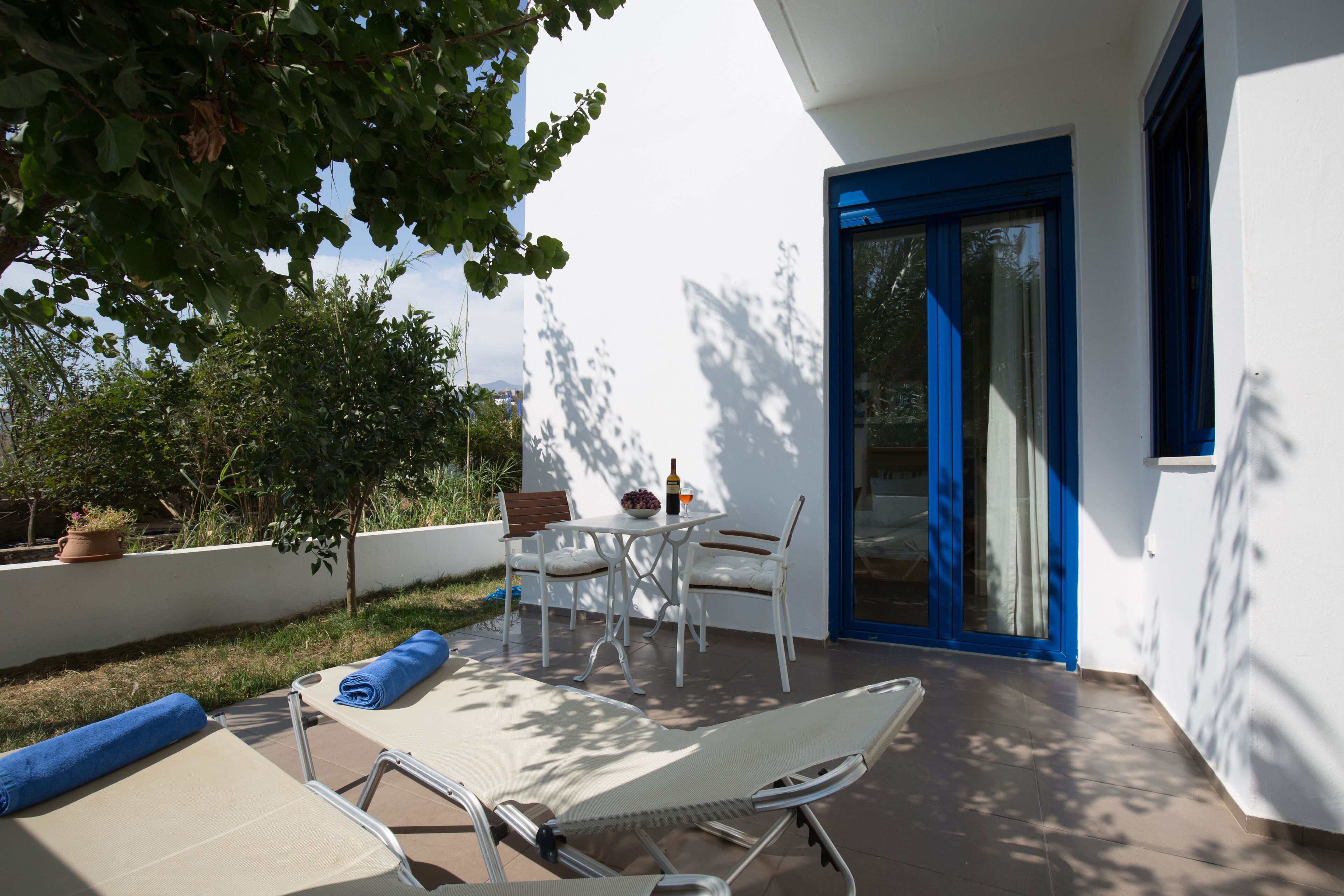Un patio con tavolo e sedie, una poltrona da relax e un vaso con una pianta.