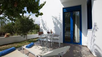 Un patio con tavolo e sedie, una poltrona da relax e un vaso con una pianta.