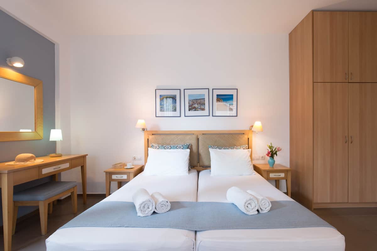 Un lit double avec deux oreillers, une table de chevet avec une lampe, un bureau avec une chaise et une armoire.
