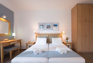 A double bed with two pillows, a bedside table with a lamp, a desk with a chair, and a wardrobe. - Anna Plakias Apartments (Agios Vasileios)