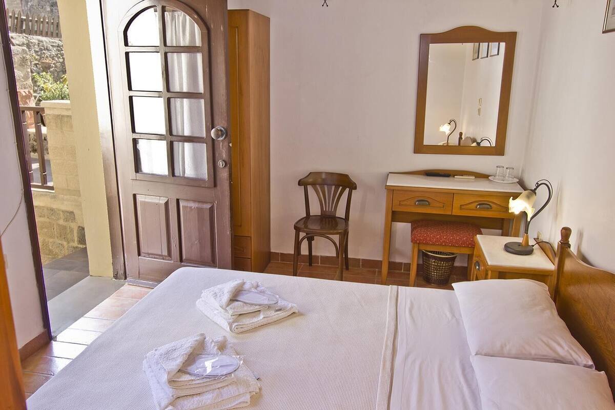 Une chambre d’hôtel comprenant un lit, un bureau avec une chaise, une commode et un miroir.