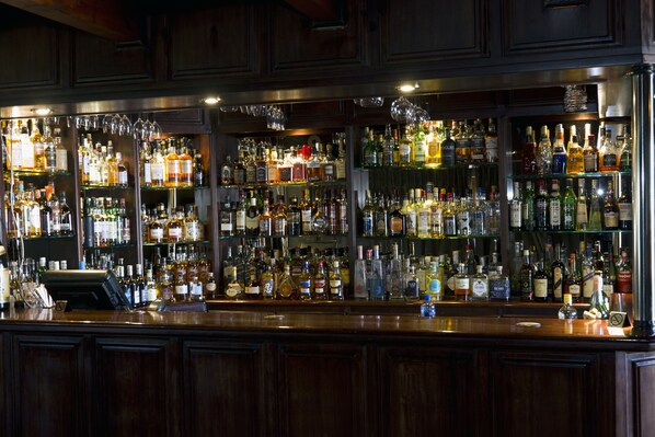 Una barra con varios estantes llenos de botellas y copas.