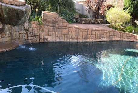 Una piscina al aire libre, sillones reclinables de piscina