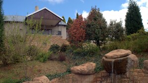 Una casa con un muro de contención de piedra y una pequeña cascada.