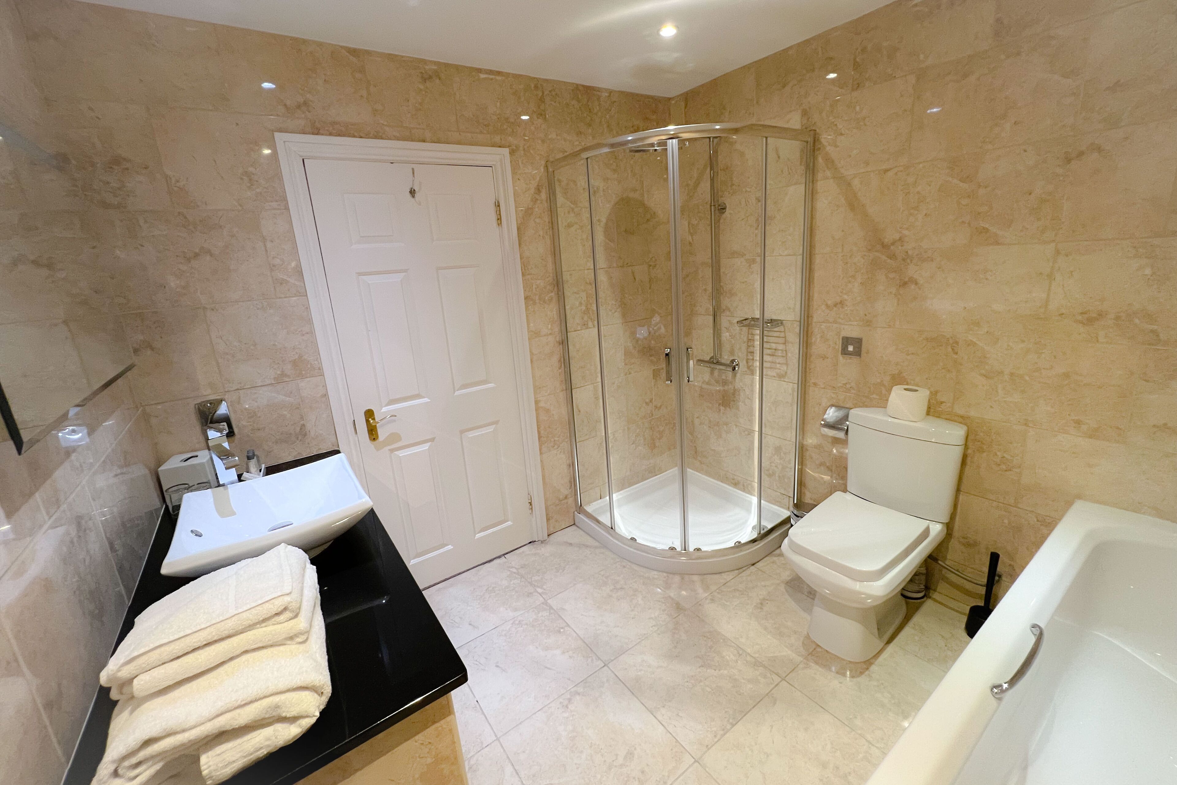 Une salle de bain moderne avec une douche à parois de verre, des toilettes blanches et une baignoire.