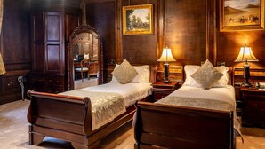 Une chambre d’hôtel avec deux lits en bois, un grand miroir et un tableau accroché au mur.