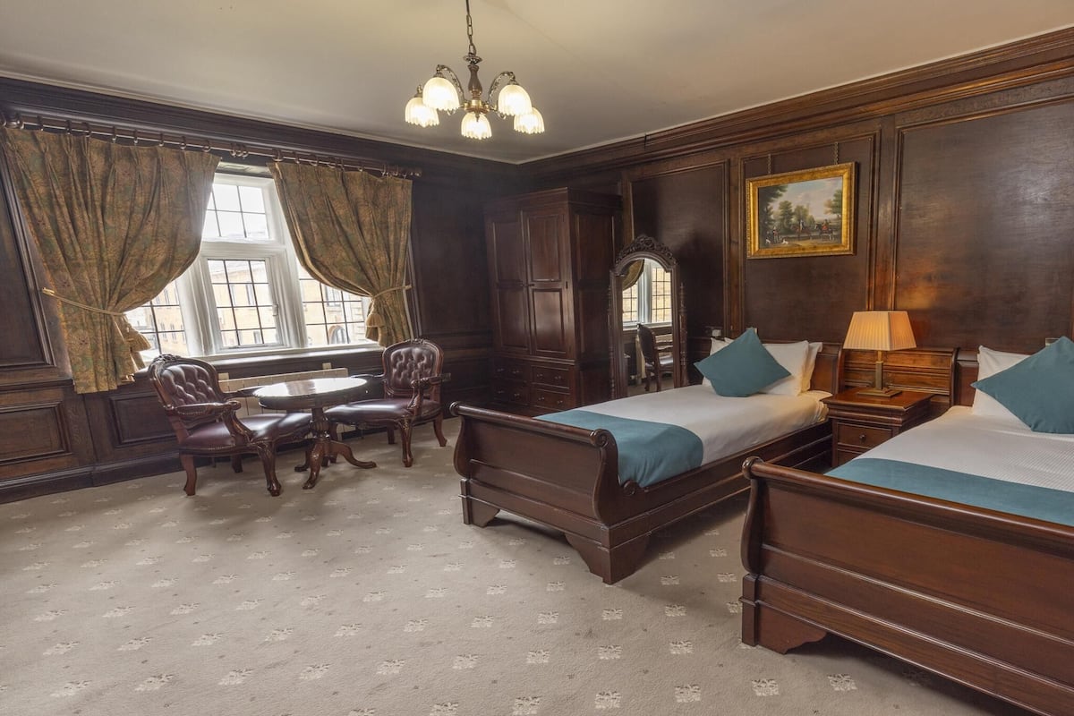 A traditional room with two wooden beds, a desk, and a chair.