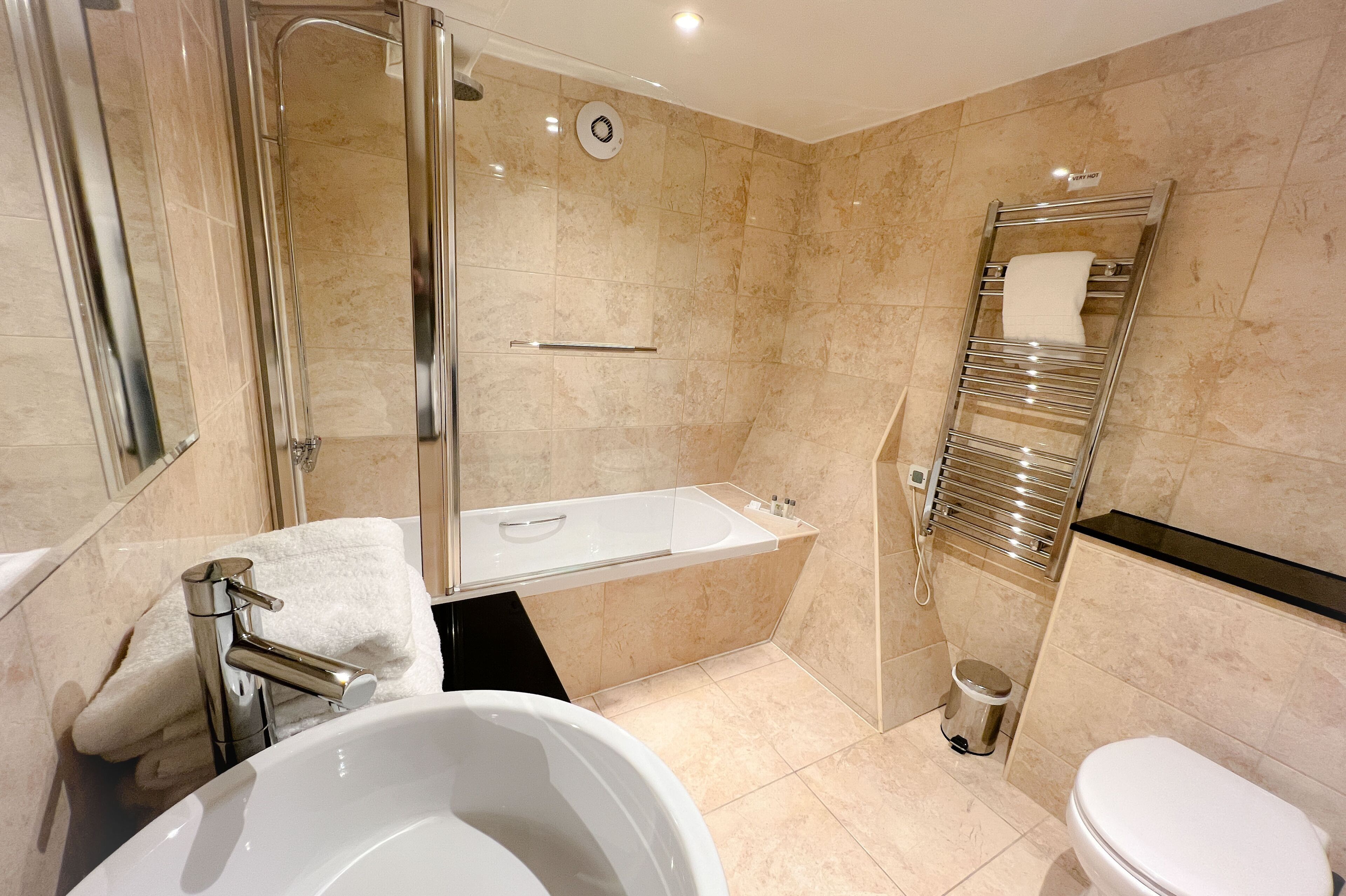 A modern bathroom with a bathtub, toilet, and shower.