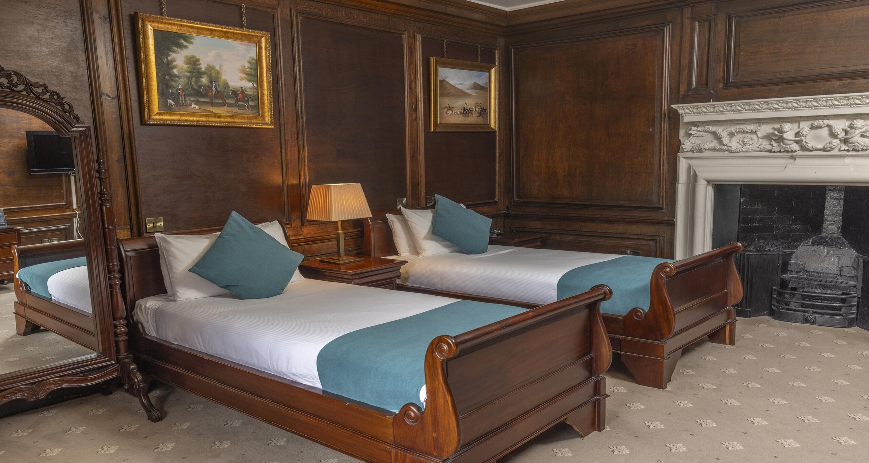Une pièce avec deux lits en bois, une cheminée et des tableaux encadrés accrochés au mur.